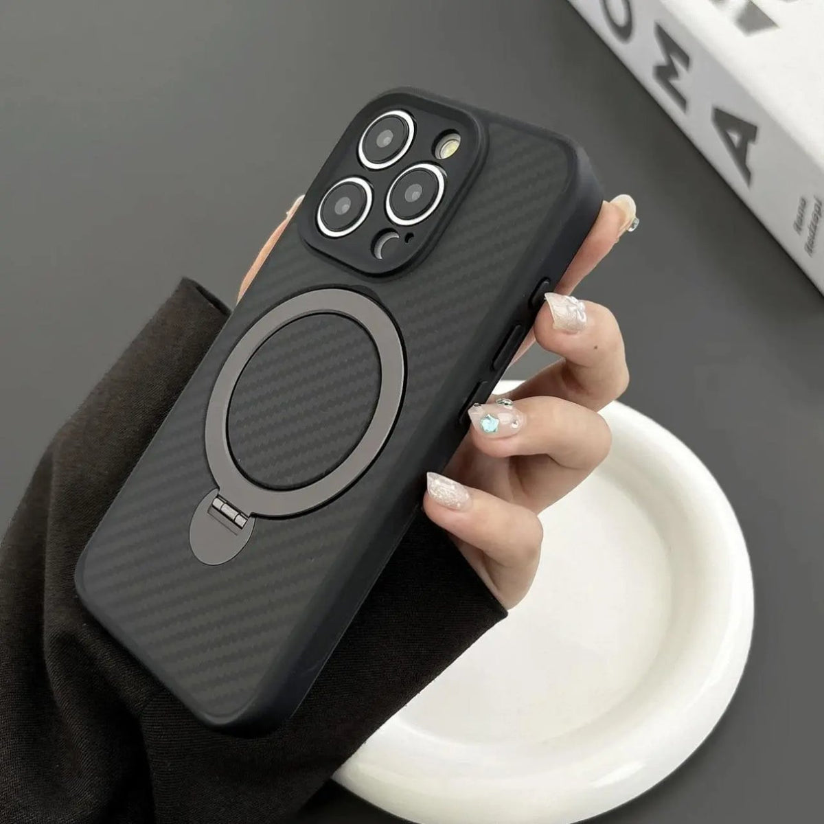 SecureGrip Carbon 360 iPhone case in black held in hand, showcasing carbon fiber texture, MagSafe ring, and slim design.