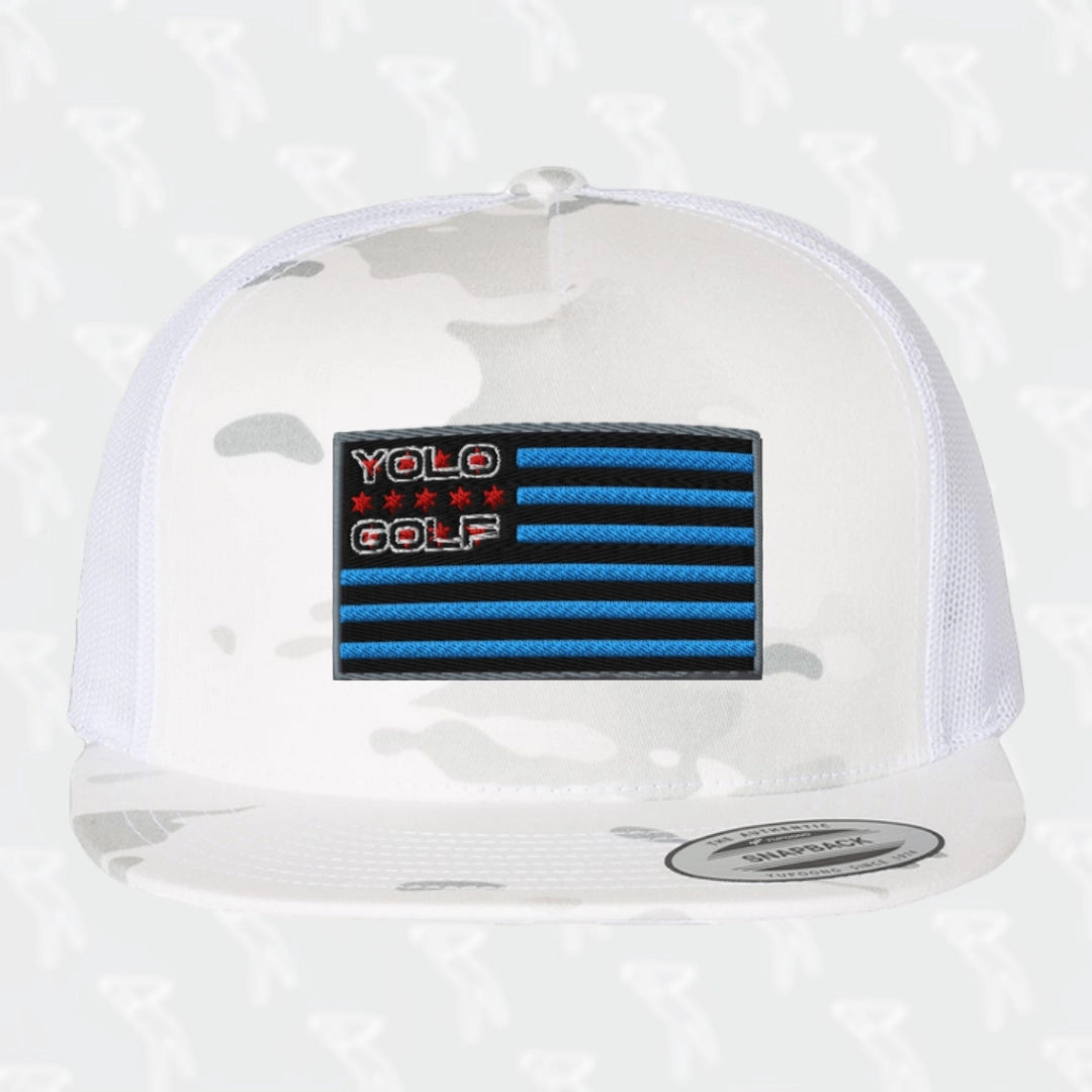 #YOLO Golf-USA Flag Multi-Camo Alpine White Trucker Hat with embroidered blue and black USA flag design on the front panel, featuring a white mesh back and snapback closure.