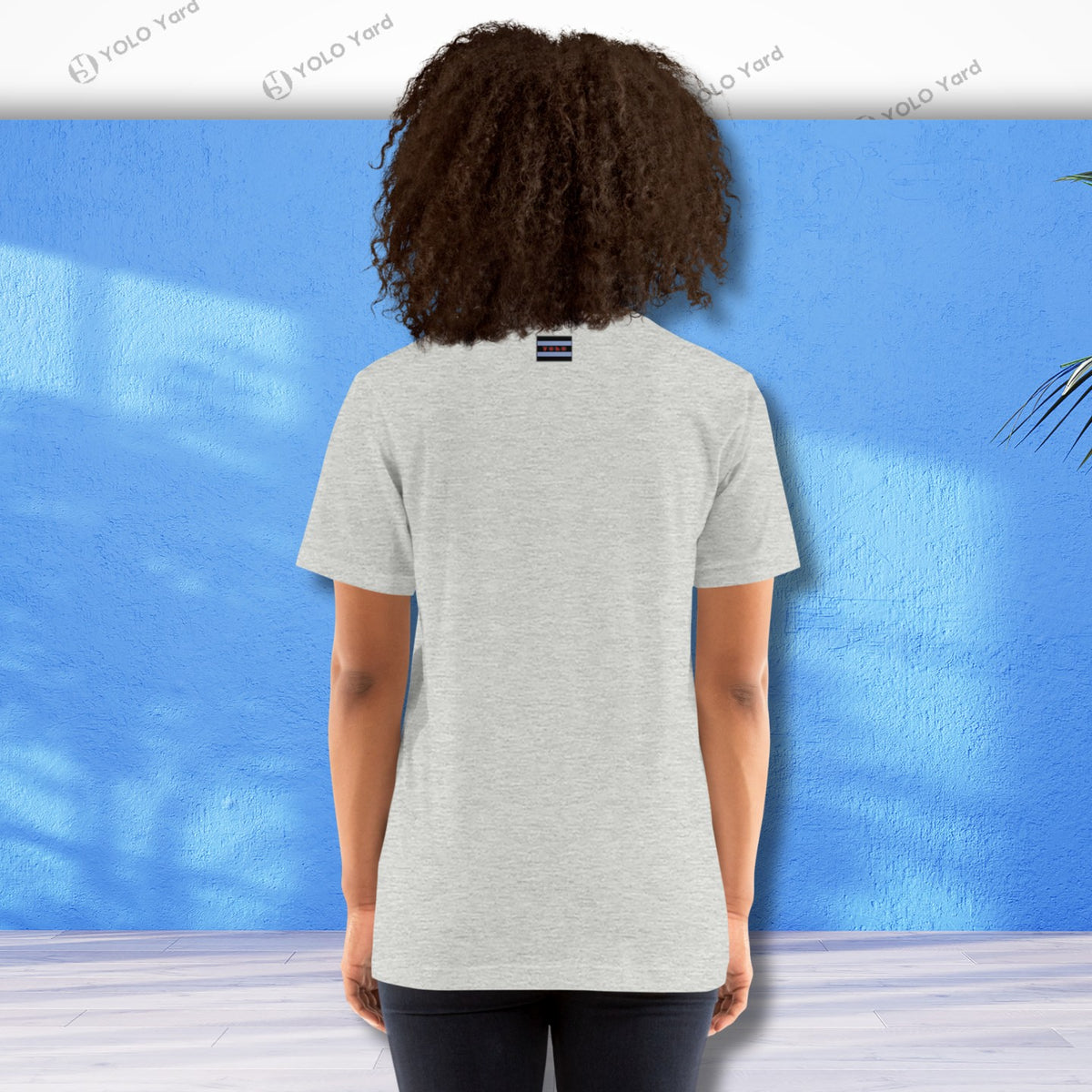 Back view of a light gray YOLO Sport t-shirt worn by a woman. Simple and comfortable design with a small logo on the upper back.