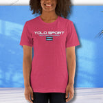 Pink YOLO Sport unisex t-shirt worn by a woman against a blue wall. Lightweight and breathable fabric for casual or active use.