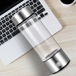 AquaPure Hydrogen Water Bottle placed on a desk next to a laptop, showcasing its sleek and portable design.