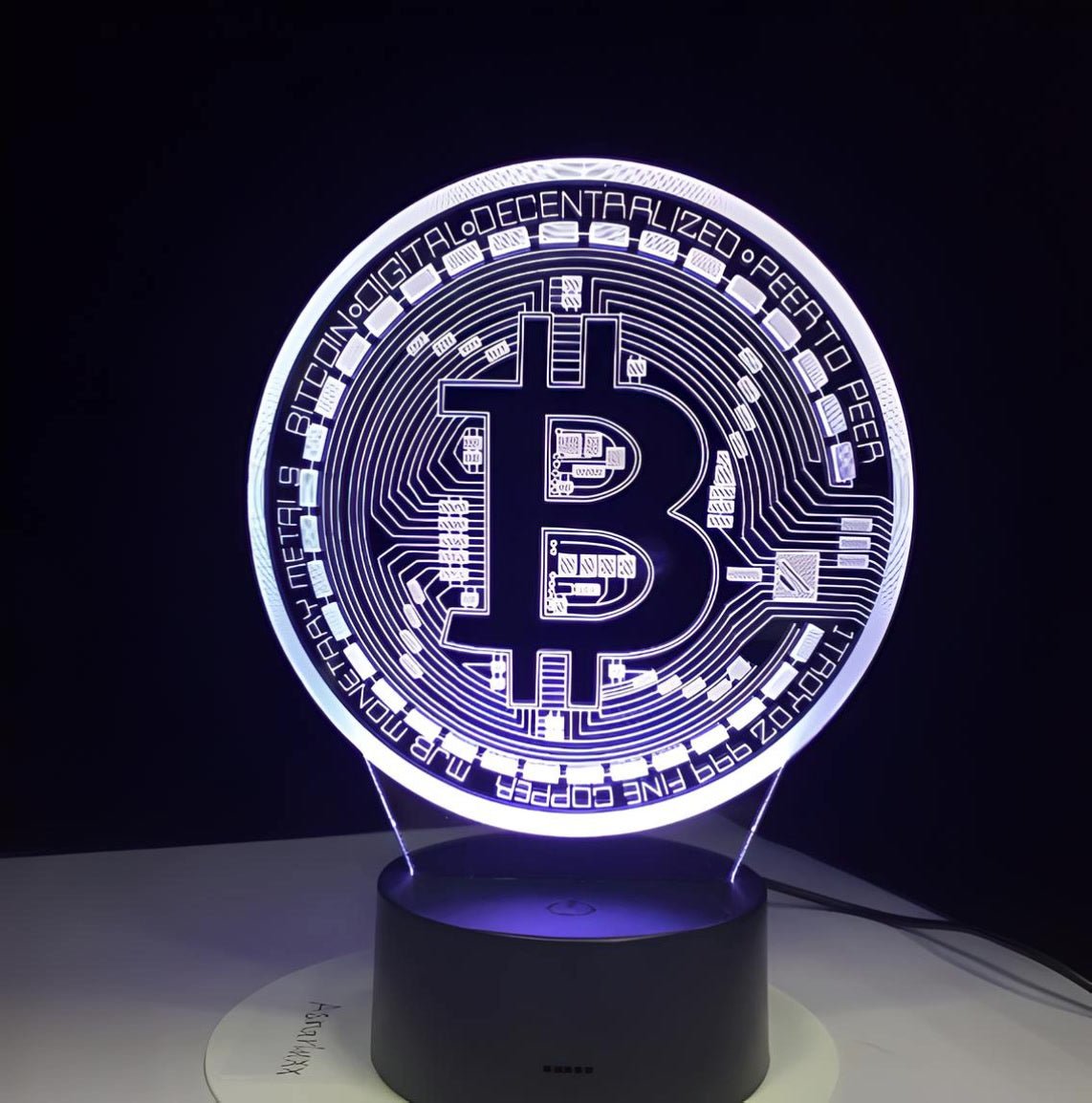 White-lit Bitcoin 3D LED desk lamp with a black base, offering a clean and modern aesthetic for home or office.