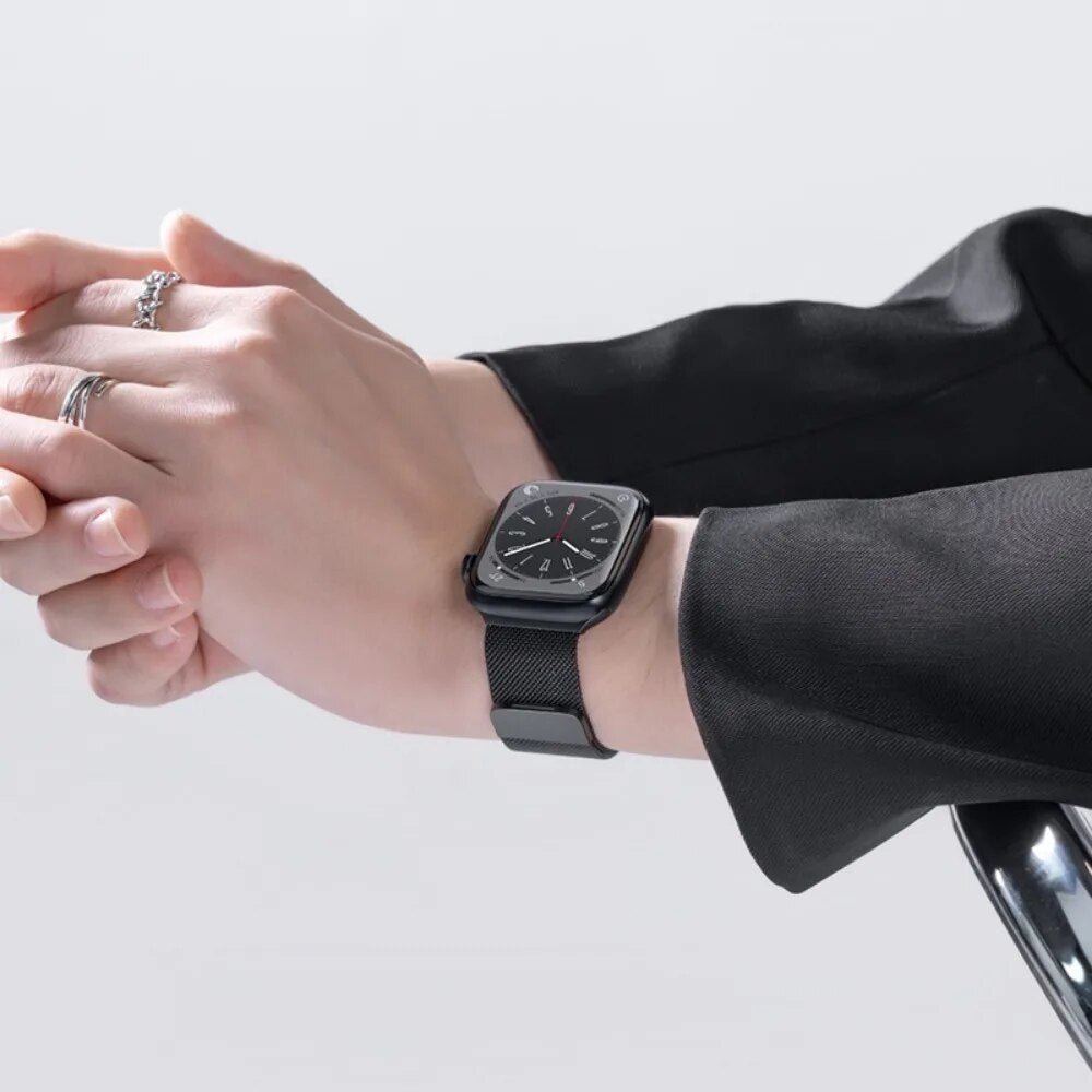 Close-up of a person wearing a black Milanese loop strap on an Apple Watch, emphasizing its elegant and professional appearance.