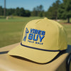 Yellow 'Vibes Guy' golf rope cap with blue embroidery, golfer logo, and #YOLO Golf branding, displayed outdoors on a golf cart.