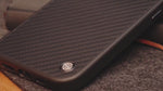 Detailed view of carbon fiber texture on aramid fiber iPhone case, emphasizing premium build quality. Manufactured by NILLKIN.