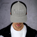 Heather gray and black Sandbagger trucker hat worn by a woman, featuring a 