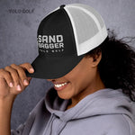 Red Sandbagger trucker hat worn by a smiling woman, highlighting its 