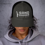 Dark gray Sandbagger trucker hat worn by a woman, featuring a 