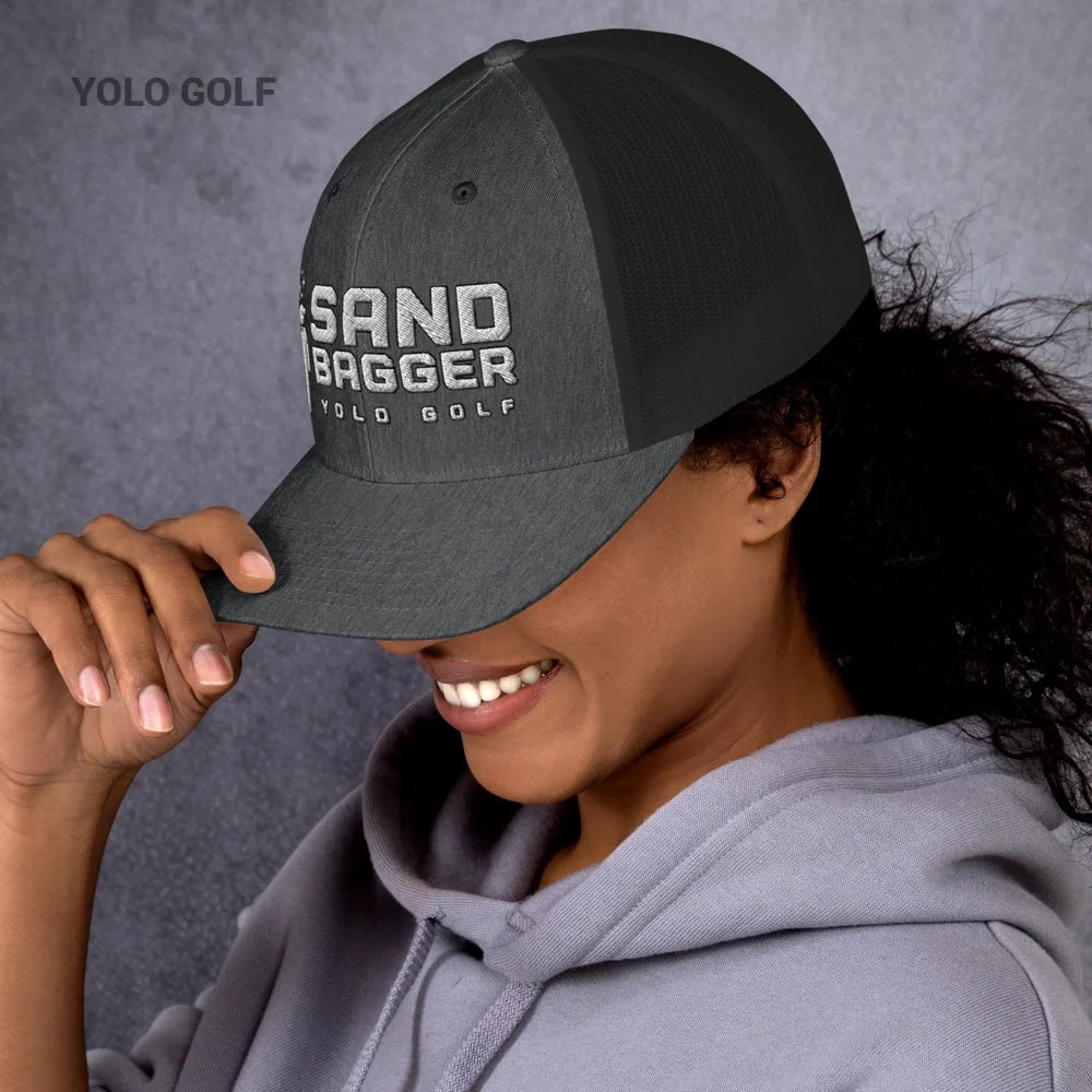 Charcoal gray Sandbagger trucker hat worn by a smiling woman, showcasing its 