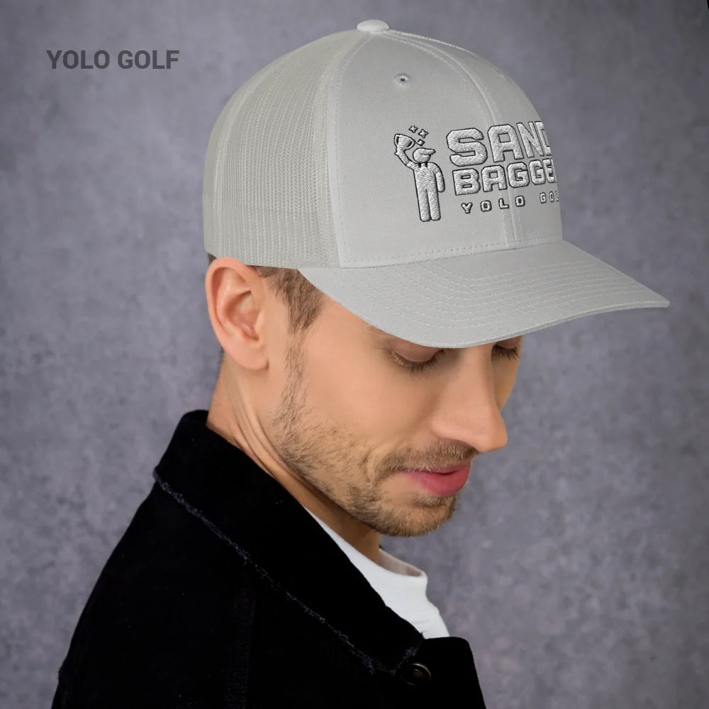 Green Sandbagger trucker hat worn by a man, featuring a 