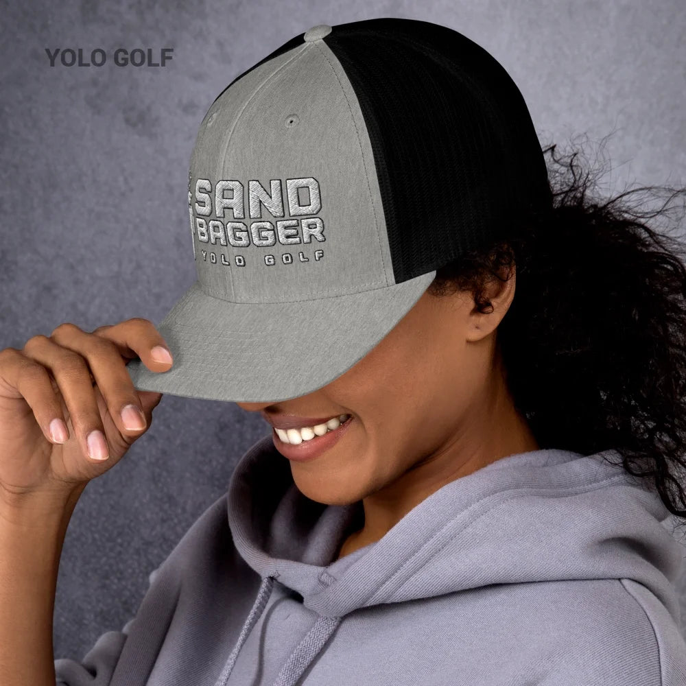 Green Sandbagger trucker hat worn by a smiling woman, featuring a 